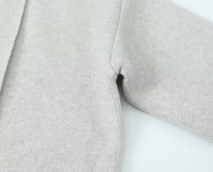 Detailed close-up showing the precise underarm seam and fine knit texture of the light gray cardigan