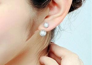 Detailed view of silver double-sided crystal ball earrings on model ear lobe