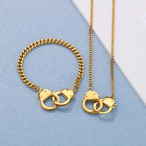 Detail view of gold Cuban chain necklace and bracelet set featuring handcuff charms