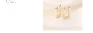 Macro shot of rectangular gold stainless steel hoop earrings on white silk fabric