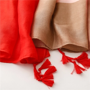 Close-up of red and light brown cotton-linen scarf with detailed fabric texture and tassels