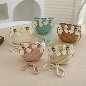 Détail de sacs à bandoulière en paille tissés à la main avec cerises et nœuds décoratifs