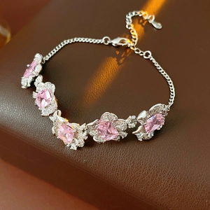 Detailed view of silver flower bracelet with pink stones and zircon accents on textured surface