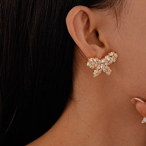 Close-up of gold butterfly stud earring with clear zircon inlay on woman ear