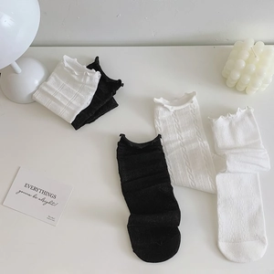 Detailed view of black and white lace mesh socks with ruffled cuffs on a minimal background