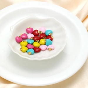 Close-up of colorful heart-shaped enamel charms with gold hanging loops for DIY jewelry