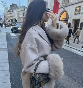 Detail of oat beige wool coat featuring luxurious faux fur cuffs in a street style look
