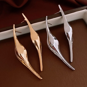 Macro shot of minimalist gold and silver streamlined earrings with a liquid metal texture