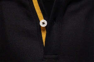 Detail of black pique polo collar with yellow contrast placket and white buttons