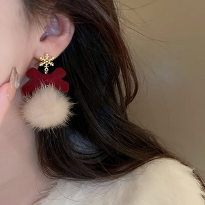Detailed view of winter earrings featuring gold snowflake, red bow, and white pom pom