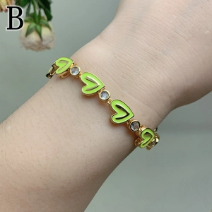 Detail of heart enamel bracelet with cubic zirconia on female wrist in gold finish