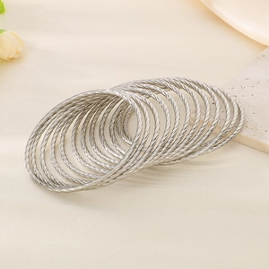 Detailed view of silver layered twist bangles with spiral texture on a stone surface