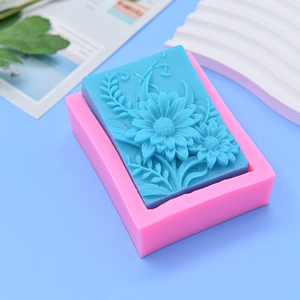 Pink silicone sunflower mold with blue embossed rectangle soap on blue background
