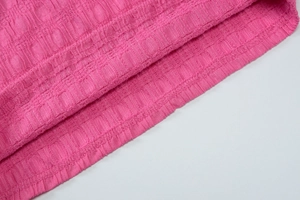 Détail du tissu en maille rose à carreaux texturés avec des coutures précises sur le haut