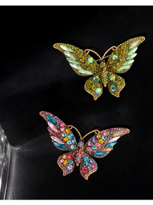 Macro shot of two luxurious crystal butterfly brooches with colorful rhinestones and gold base