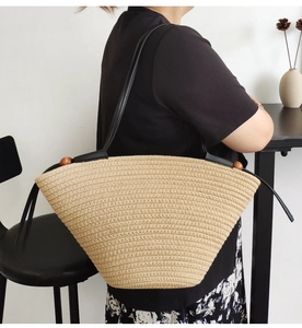 Detail of beige woven cotton rope tote bag featuring black leather straps and wood beads