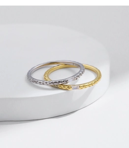 Detail of s925 silver and gold rings featuring hammered texture and emerald cut zircon