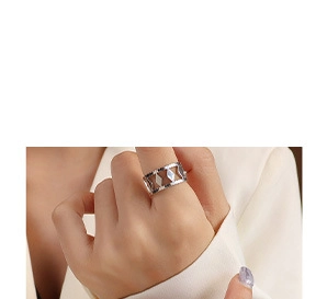 Close-up of a silver-toned wide band ring featuring geometric hollow diamond patterns