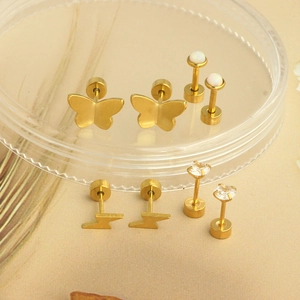 Set of four gold stud earrings featuring butterfly, lightning bolt, opal, and zircon charms