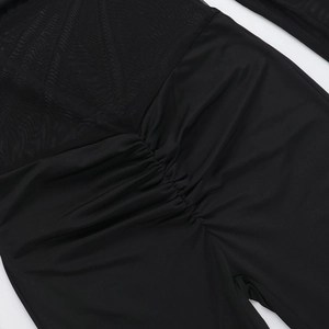 Detailansicht der schwarzen Netz-Nähte und gerafften Stricktextur auf dem Jumpsuit