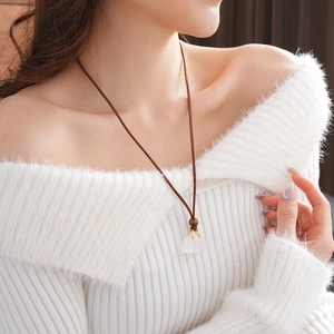 Close-up of a retro leather necklace featuring a faux stone pendant and a wooden bead detail
