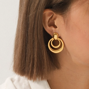 Close-up of dual gold circular hoop earrings worn by a model showcasing metallic luster