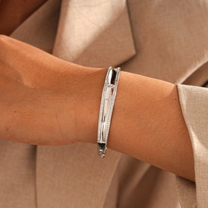 Detailed view of silver-toned bangle with pavé-set zircons on a professional model