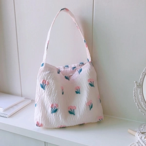 Sac à épaule en toile rose avec motif cerise et texture plissée sur fond en bois blanc