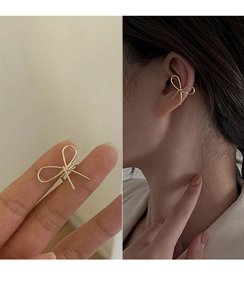 Detail of a golden bow ear cuff with a model showing the non-pierced earring style