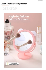 Detailed view of a pink cat-eared desk mirror with a rotating stand on a makeup vanity