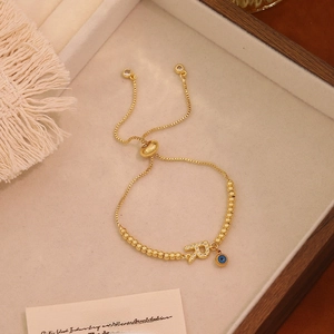 Dettaglio del bracciale Evil Eye dorato con ciondolo lettera R e cordino regolabile