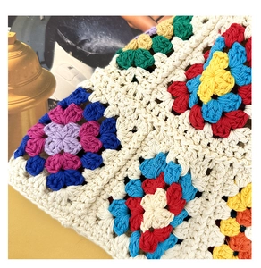Detailed macro shot of multicolor crochet floral patterns and knit texture on a wool hat