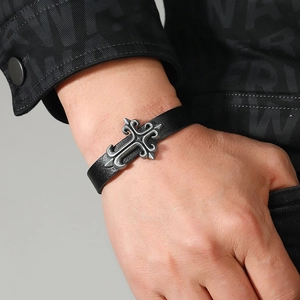 Close-up of a vintage black braided leather bracelet featuring a silver gothic cross