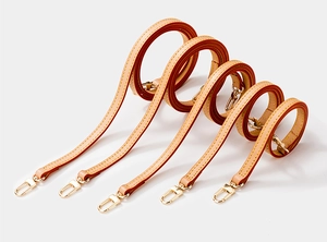 Detail of leather bag straps with yellow stitching and gold metal swivel hooks