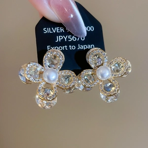 Vue macro de boucles d'oreilles fleurs dorées avec perles blanches et zircons brillants