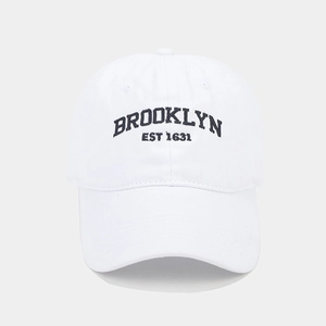 Detailed view of Brooklyn embroidery on white washed cotton baseball cap with ventilation holes