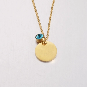 Detailed close-up of a gold necklace with a blue crystal and round mirror tag