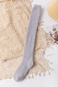 Detailed texture of thick grey-purple coral fleece over-knee socks on lace background