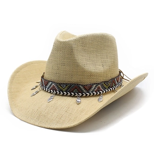 Chapeau de cowboy en paille avec bande ethnique et breloques cœur argentées sur fond blanc
