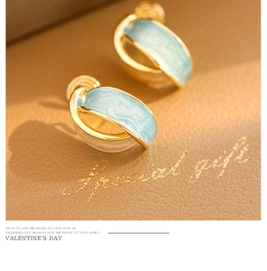 Close-up of gold hoop earrings with light blue marble enamel in a gift box