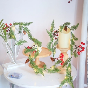 Artificial Christmas garland with LED lights, red berries, and pine cones for home decor