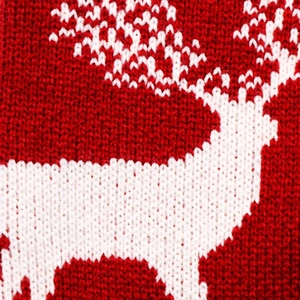 Macro shot of knitted white reindeer pattern on a red festive Christmas stocking fabric