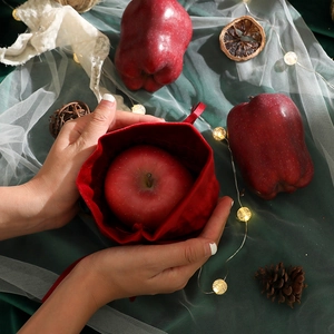 Red velvet Christmas drawstring gift bag with apple and warm fairy lights decor