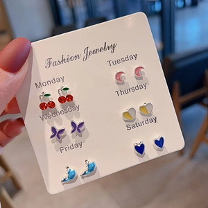 Close-up of 6 pairs of colorful stud earrings featuring cherry, butterfly and heart shapes