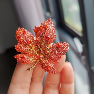 Close-up of elegant maple leaf brooch with red and orange crystals on alloy base