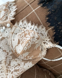 Detailed macro view of beige lace bra with black eyelash fringe and decorative buttons