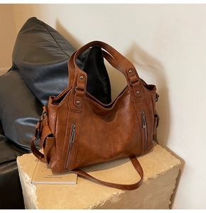 Detailed macro view of the brown leather texture and silver zipper of this large tote bag