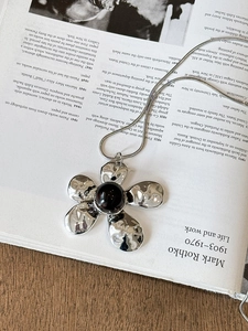 Detail of silver flower pendant necklace with resin center on an artistic book background