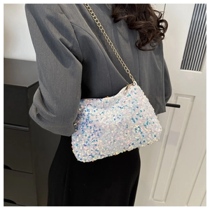 Close-up of white sequin chain bag with rainbow reflection worn by model in gray blazer