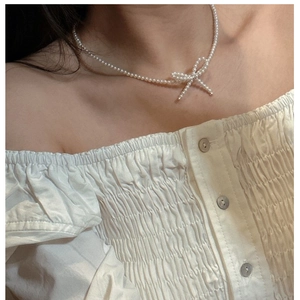 Close-up of elegant pearl bow necklace showing exquisite luster on a model's neck